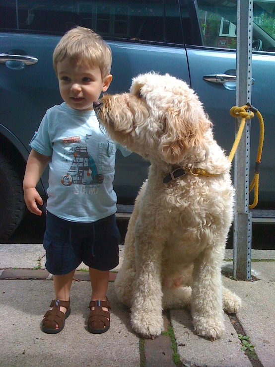 a boy standing with his pet dog outside in front of a truck