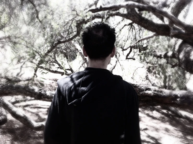 a young man standing in front of a tree nch