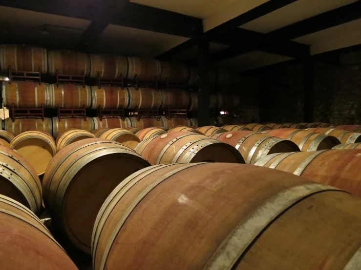 many old wine barrels are stacked high up in a room