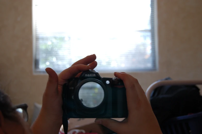 a girl holding up her camera in front of a window