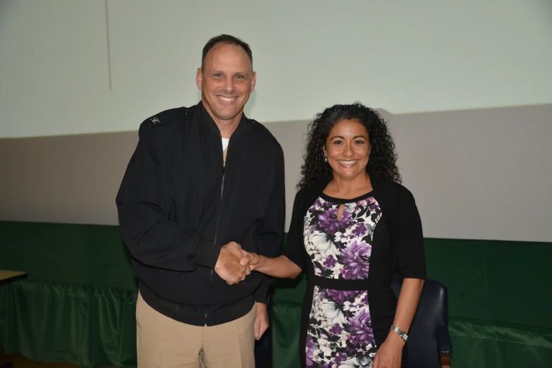 two people shaking hands near a screen