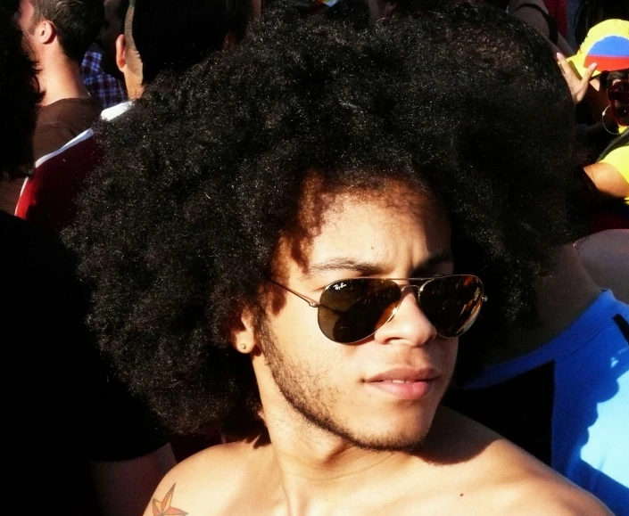 an afro man wearing sun glasses with an unruled side part of his hair