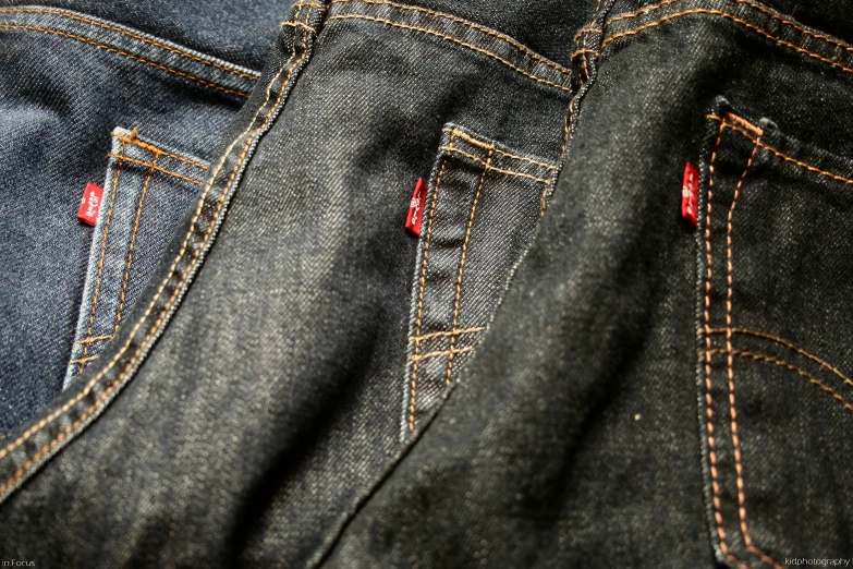 two jeans and some red stitching are laying on a table