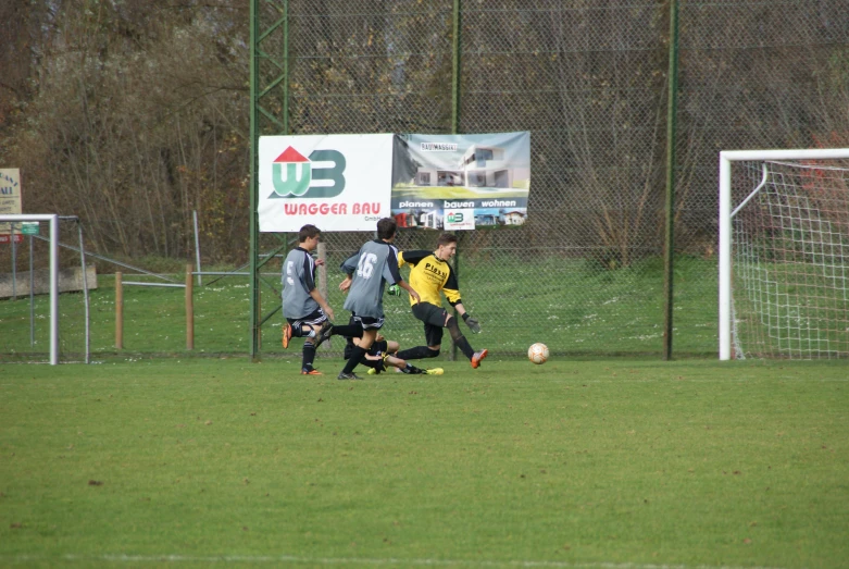 three young soccer players, including two boys and one boy, are playing soccer on a grass field