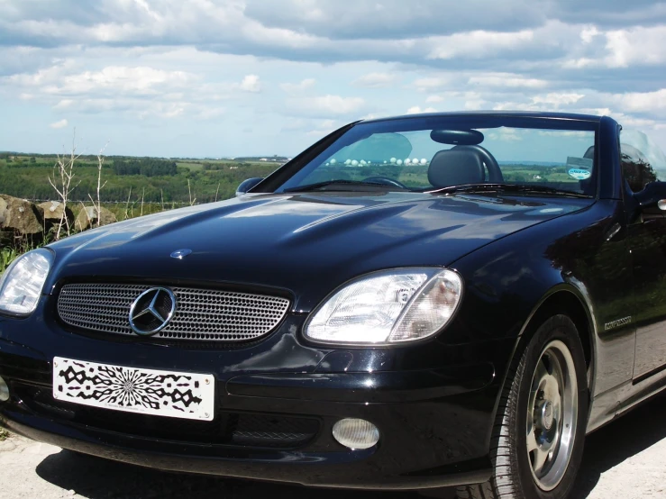 a mercedes benz roadster is parked with a sky background