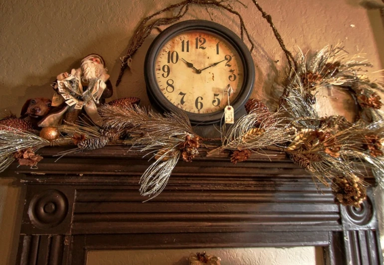 a clock on a mantel decorated with holiday decorations