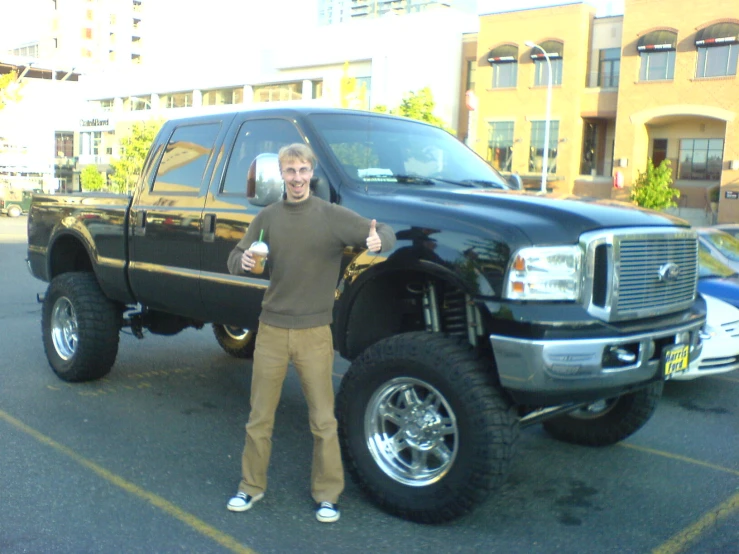 a man with two thumbs up standing in front of a truck