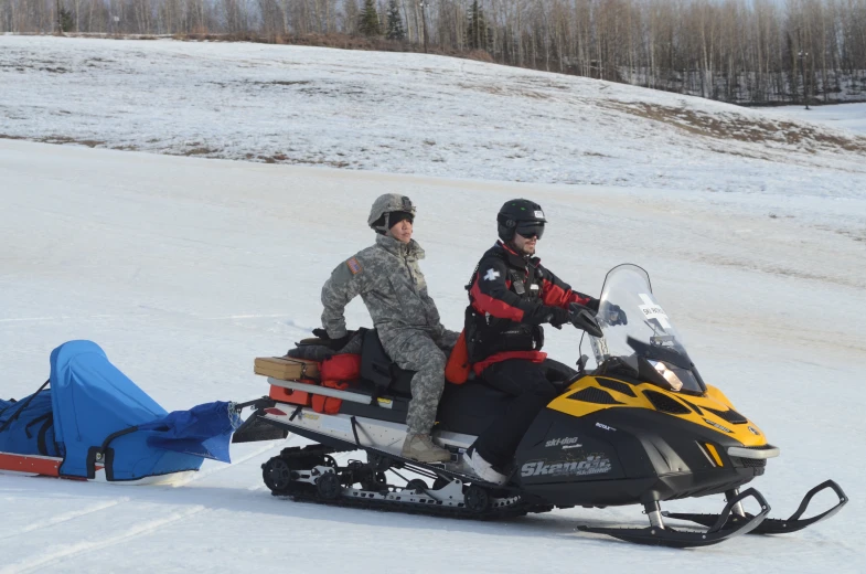 two people are sitting on a snowmobile, in the snow