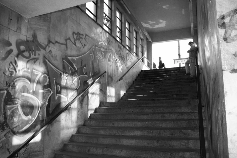 black and white pograph of graffiti on a wall behind a staircase