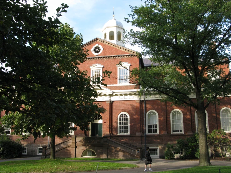 a young person standing outside an old building in front of trees