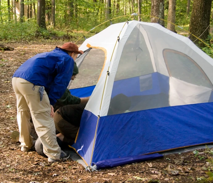 a man with a cap is placing a tent