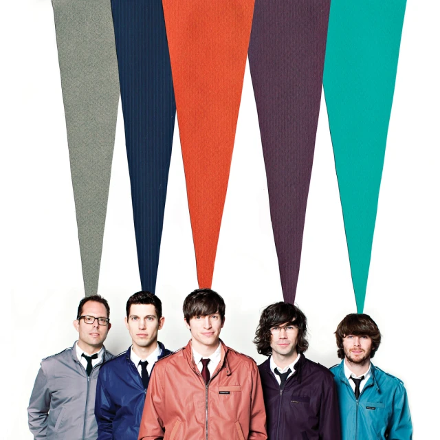 men in ties and jackets stand next to large strips of rainbow colored clothing