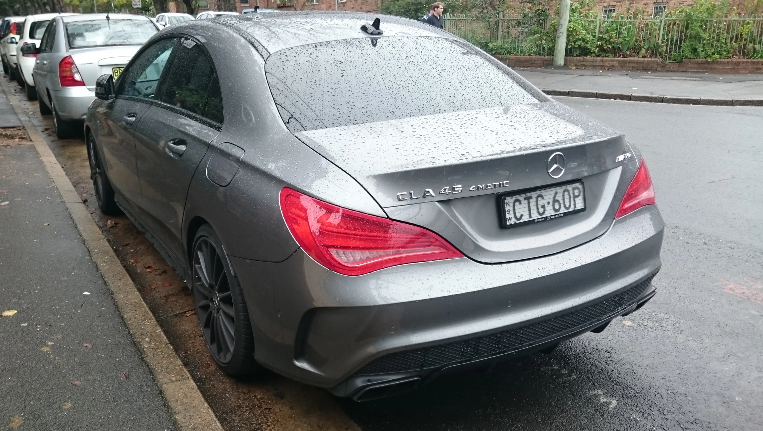 several cars parked along the curb in the rain