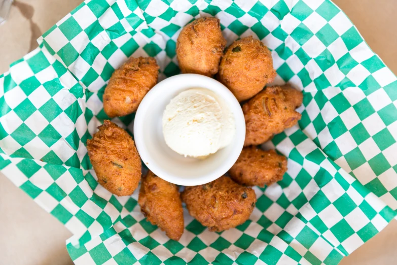a bowl full of crab cakes on top of a green and white checked paper