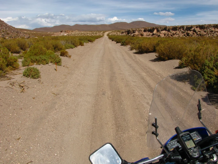 a motorcycle is driving down a dirt road in the desert