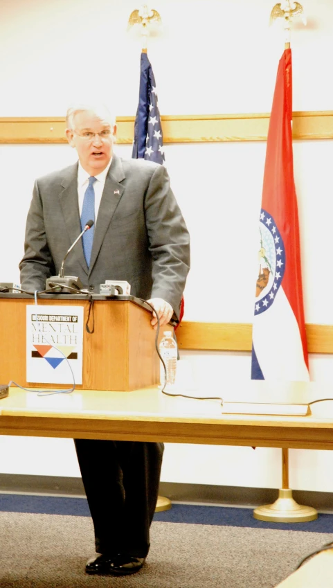 a man standing in front of a wooden podium with a microphone in his hands