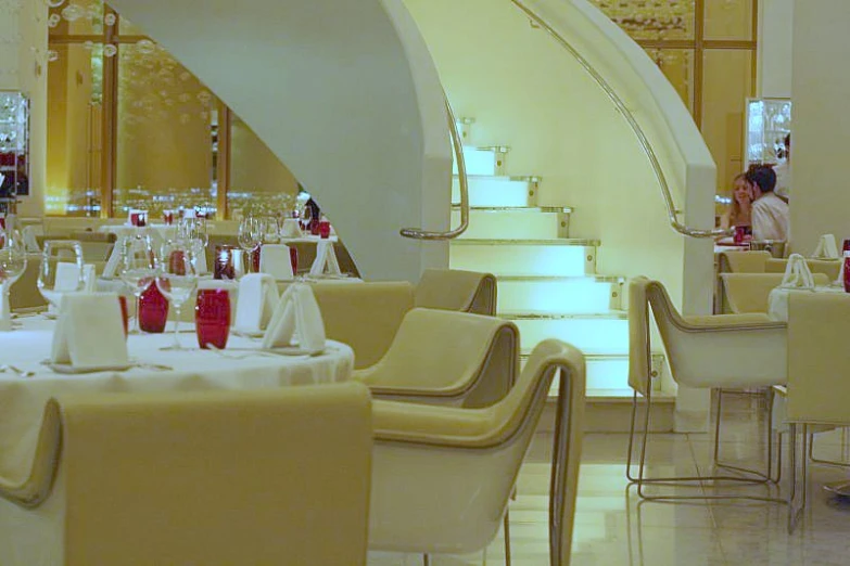 several tables covered in white cloth and wine glasses with people seated