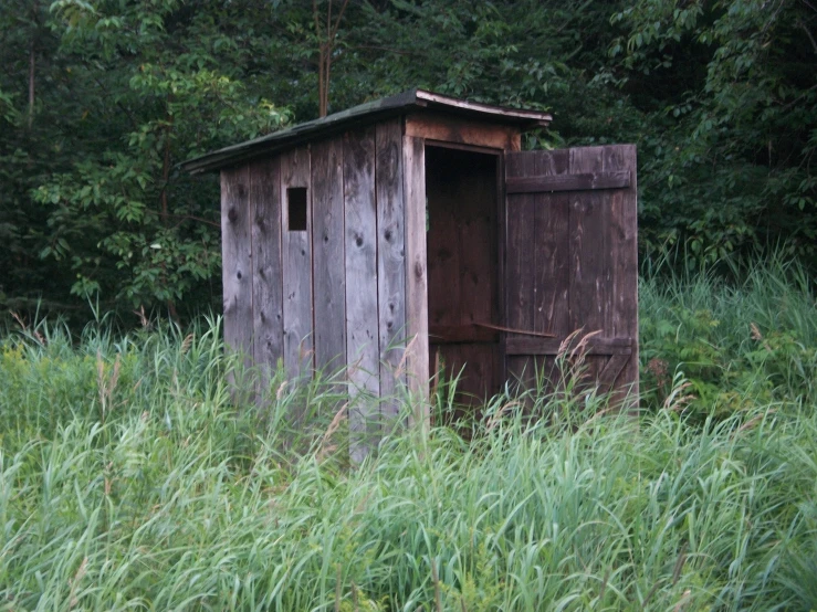 a small outhouse in a grassy area