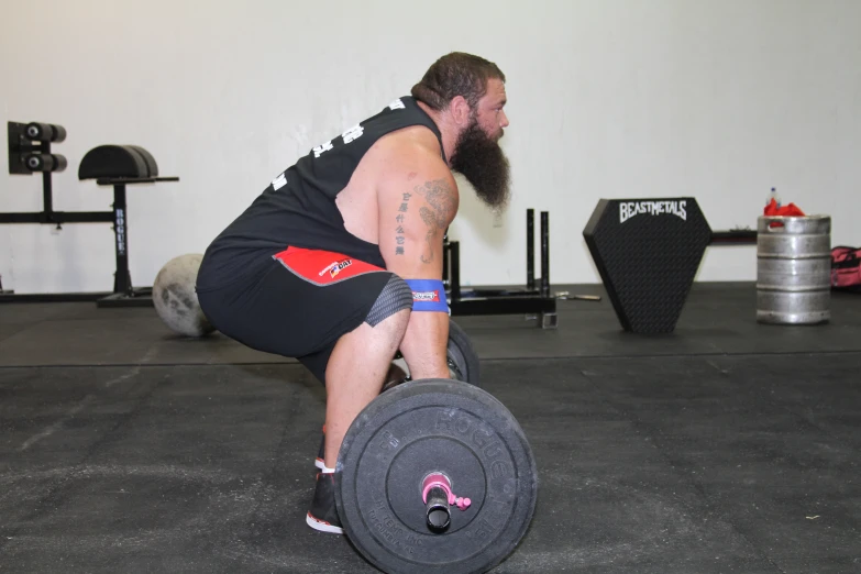 a bearded man doing squats on a weight machine