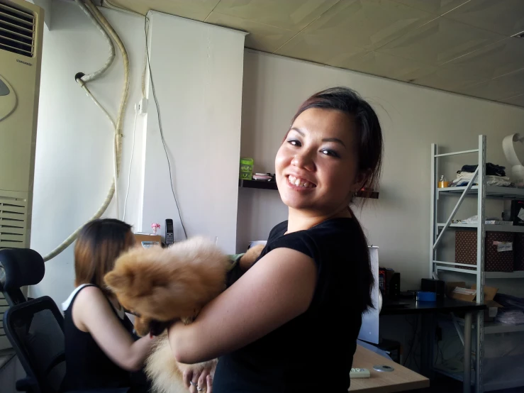 a smiling woman holding an animal while sitting in a chair