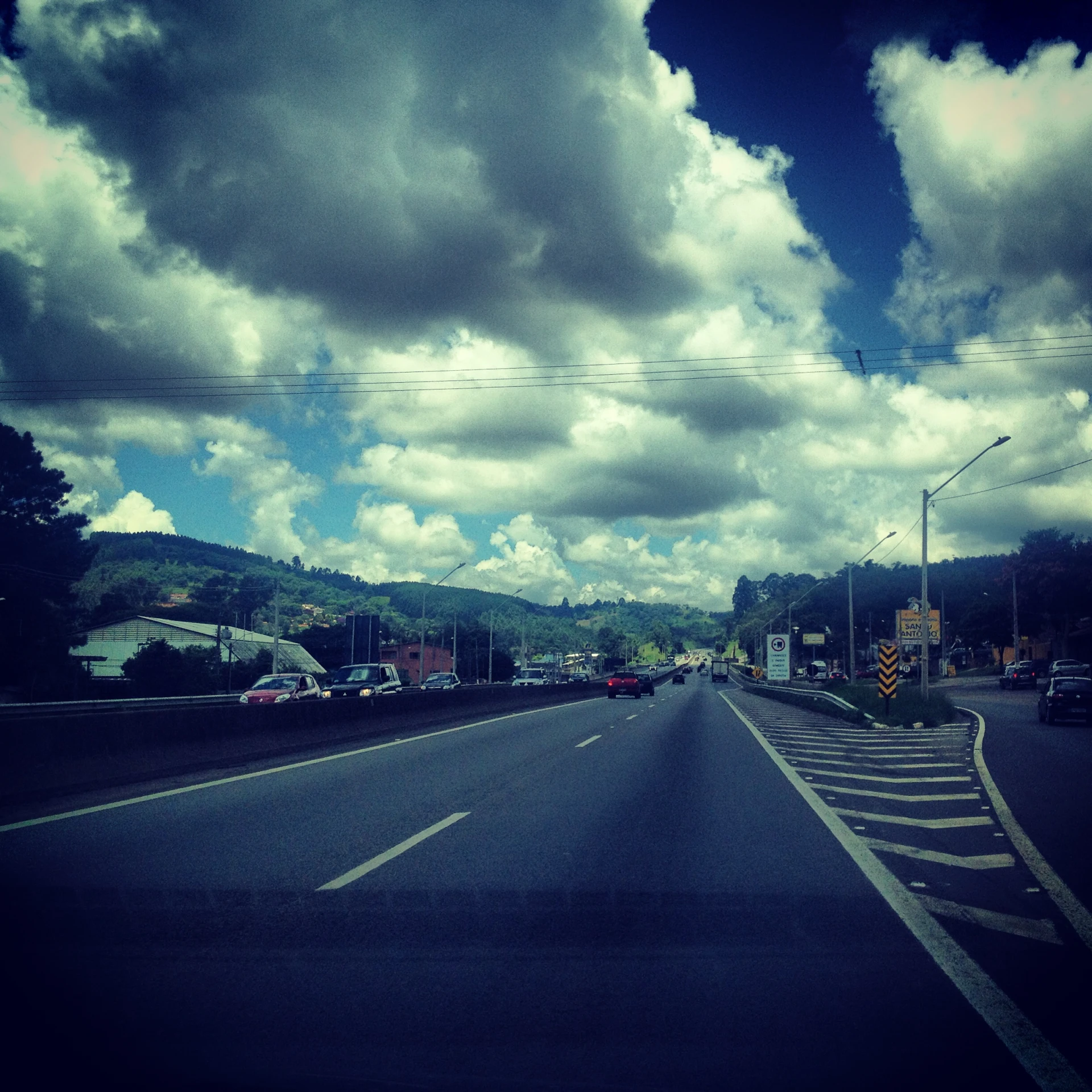 a view of an asphalt roadway under a cloudy blue sky