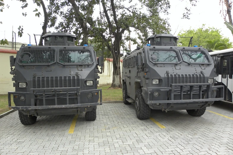 large camouflage style army vehicles on display in a parking lot