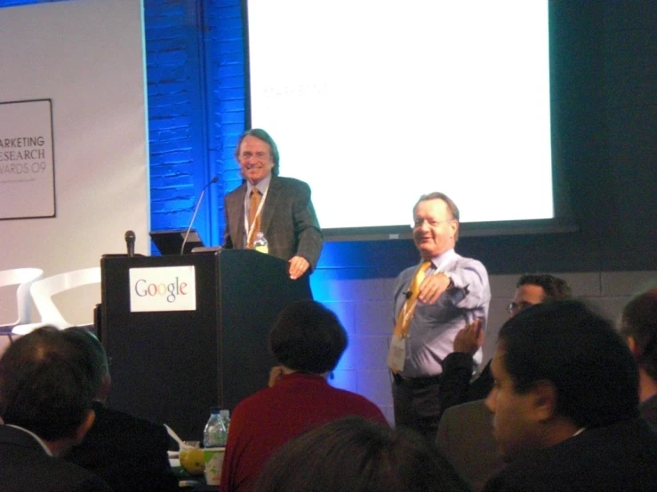 two men are giving a presentation to an audience