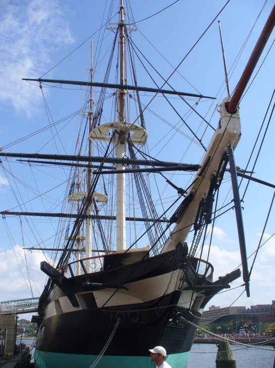 a person in white and black hat looks up at a boat in the water