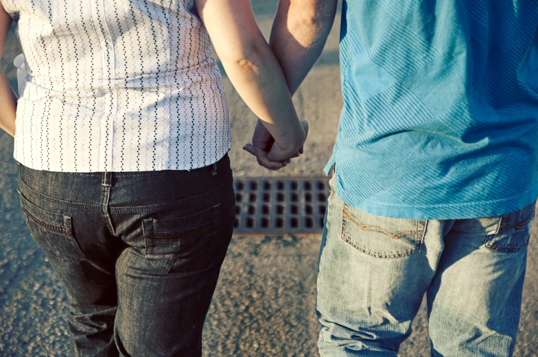 two people hold hands as they walk down the street