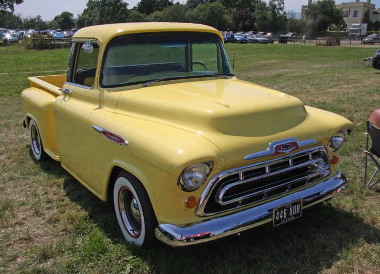 a vintage yellow truck with a person sitting on a bike in the background