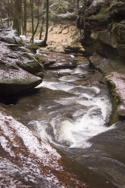 a creek flowing down a snow covered hill