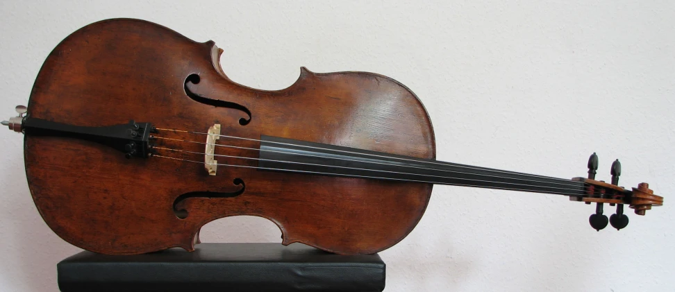 a very old, violin sits on a small wooden stand