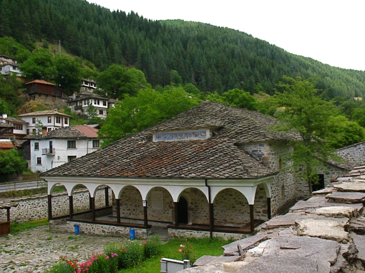 an old building with a tiled roof next to some grass and rocks