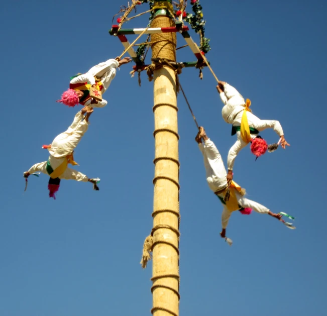 several people wearing costumes are climbing down the pole