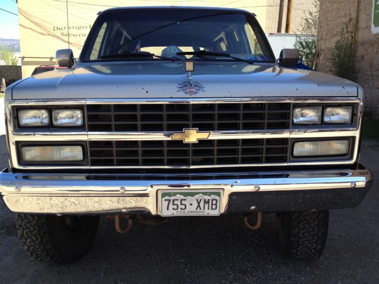 silver truck parked in a driveway with an older building