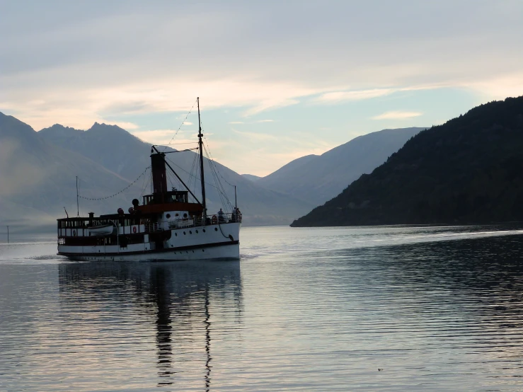 a boat on a river with mountains behind it