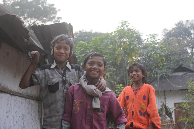 three small children standing outside next to a building