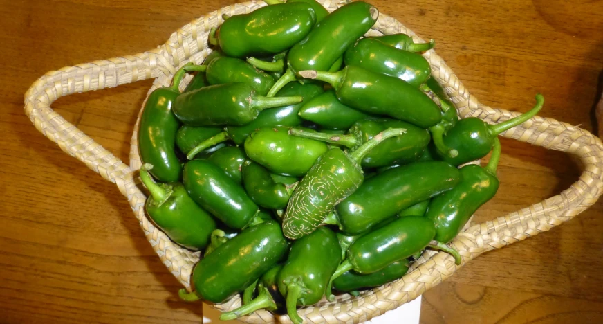 green bell peppers in a woven basket on a table