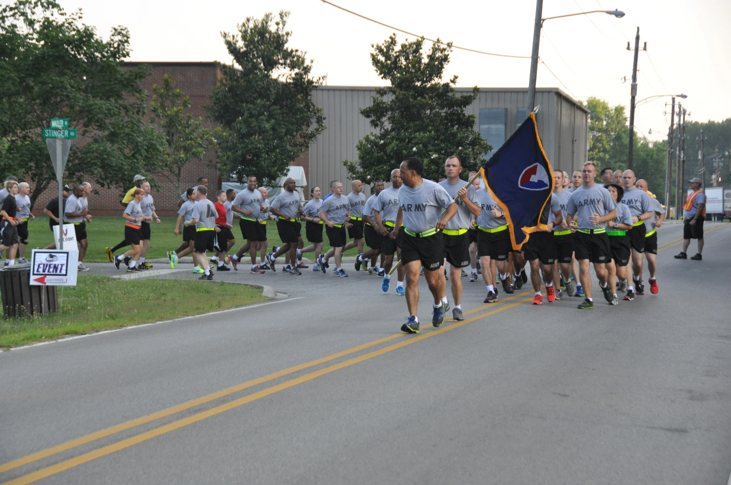 a long line of people in gray shirts walk down a road