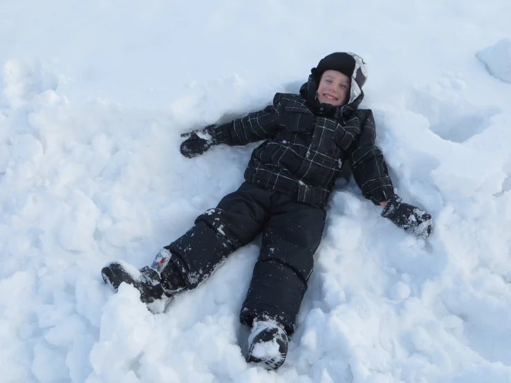  laying in snow while wearing jacket and holding gloves