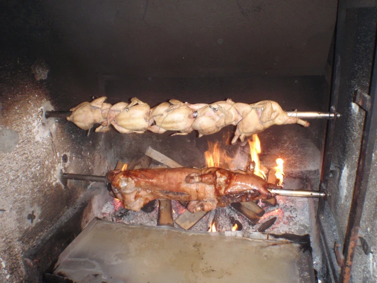 a bunch of meat cooking in a small open fire