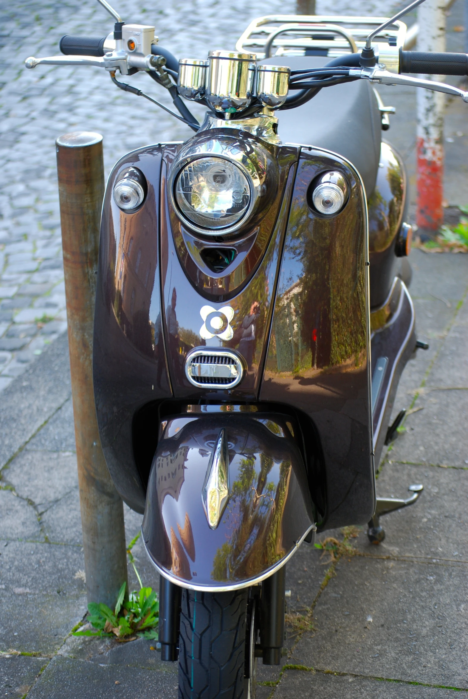 the headlight of an old fashioned moped parked on the side of the road