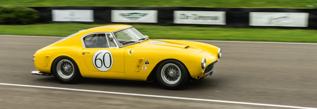 a vintage yellow race car with number sixty on the front wheel drive along the asphalt