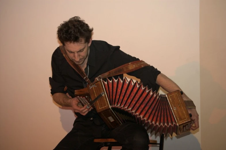 man holding an old accordion and looking at it