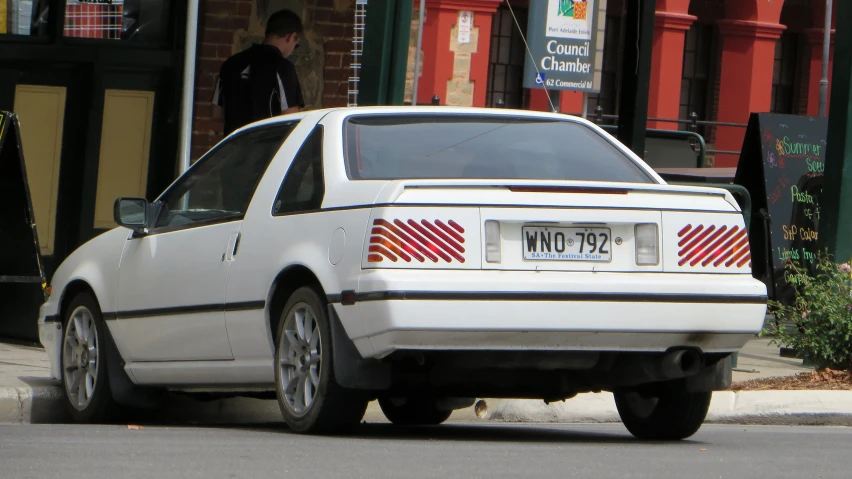 an image of a white car that is parked on the street