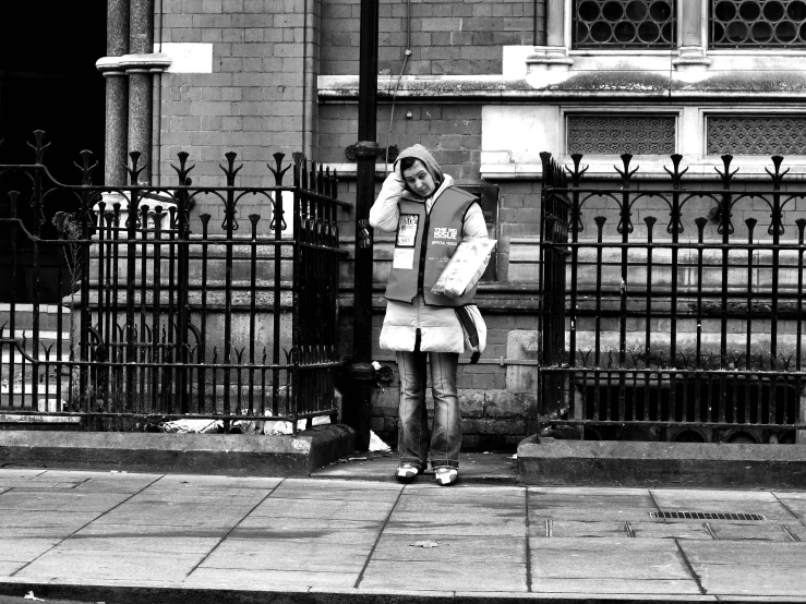 a man standing outside of an iron fence talking on a cell phone