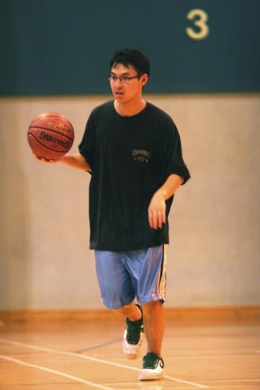 a man holding a basketball while walking on a basketball court