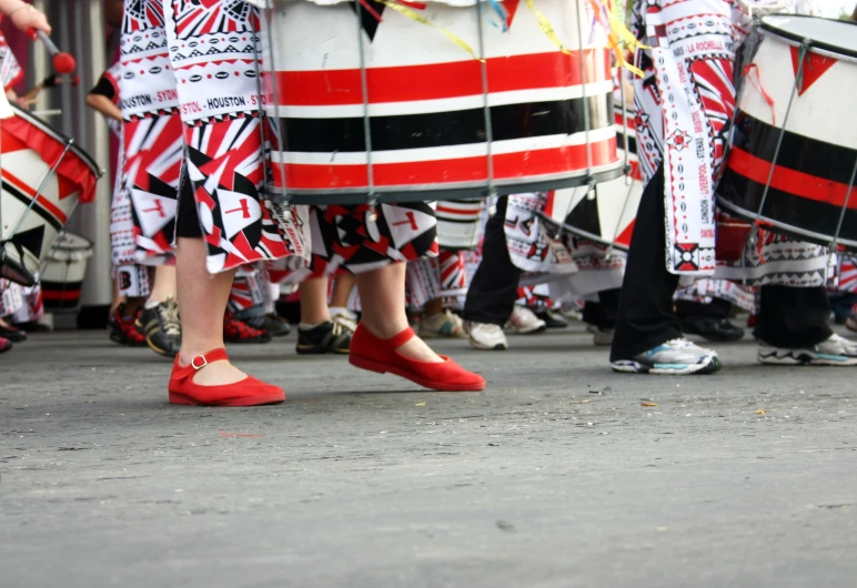 a group of people wearing red shoes and striped skirts