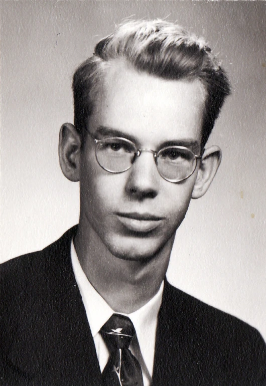 a black and white pograph of a man in glasses, wearing a suit