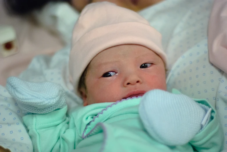 a newborn girl wearing a white hat and laying in her crib